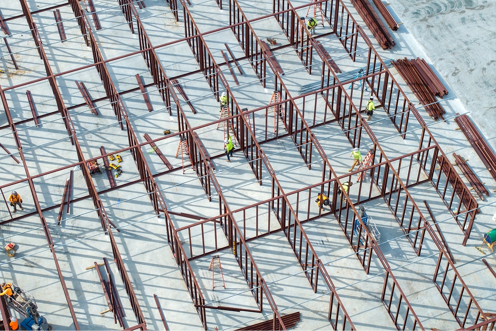 Interior de un local comercial en remodelación con estructura metálica, ductos expuestos y trabajadores instalando paneles